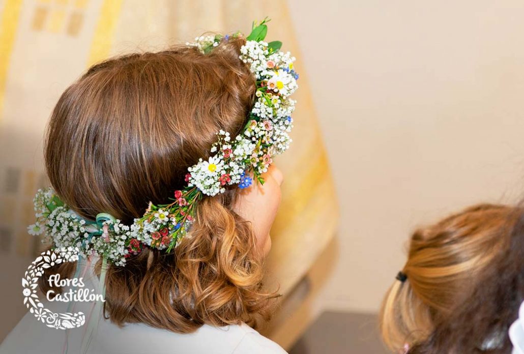niña haciendo su primera comunion con una diadema de flores